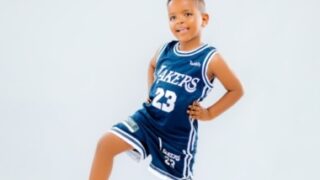 A young boy in a basketball uniform holding a basketball